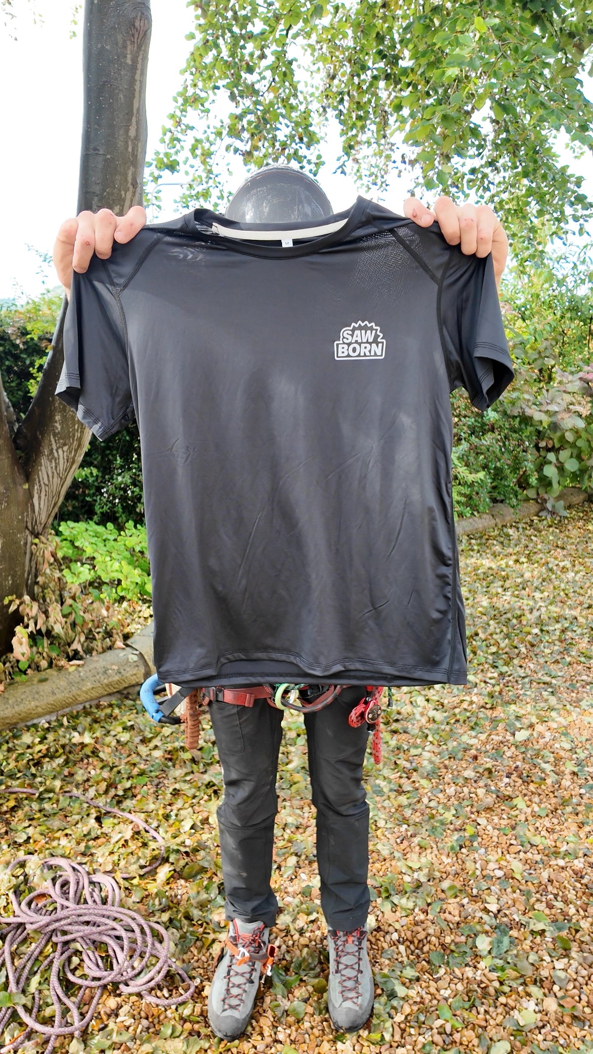 Black SawBorn Tec T-shirt held up, front view with the chest logo