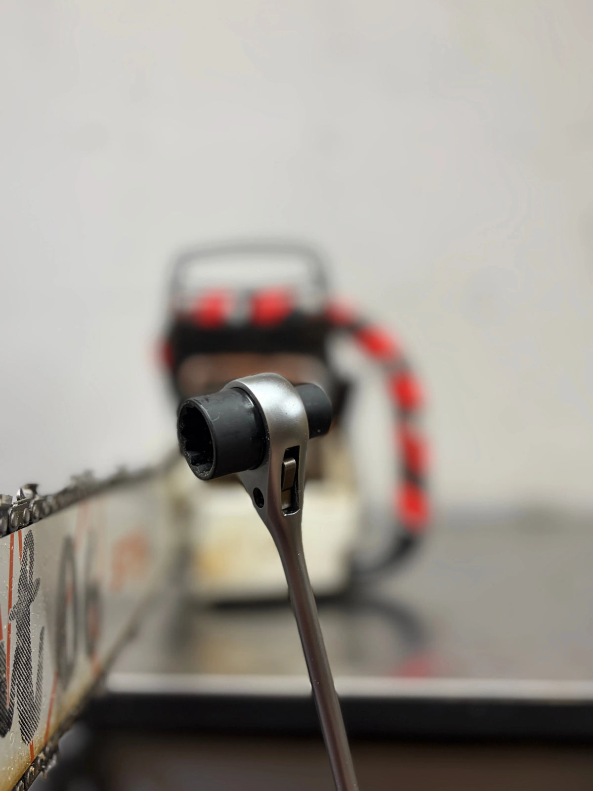 Chainsaw ratchet wrench on a bar nut, chainsaw behind